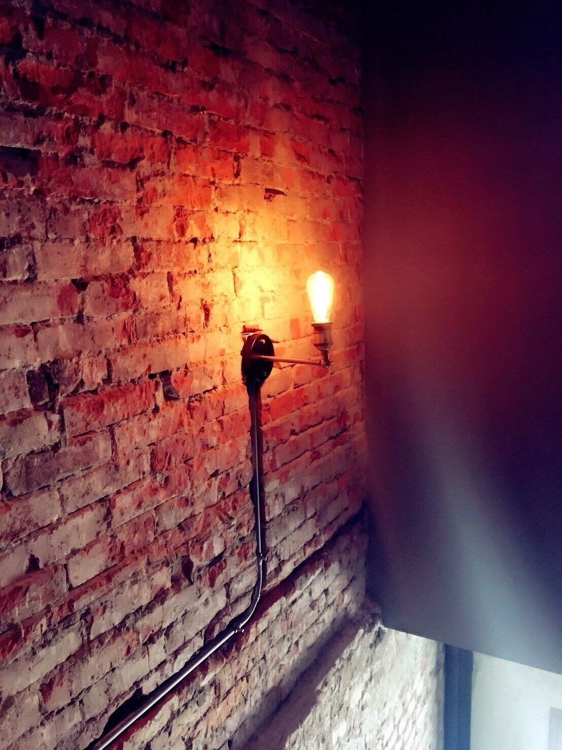 A brick wall with a single light fixture.