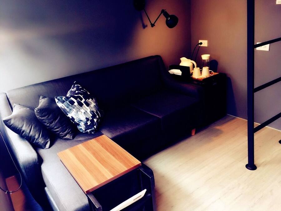 Una sala moderna con un sofá de cuero negro, una mesita de madera y una lámpara de pie negra.