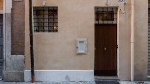 A building with a beige facade, two windows with white frames, and a wooden door. - Colonna Suite - Spanish Steps Suite & Spa (Rome)