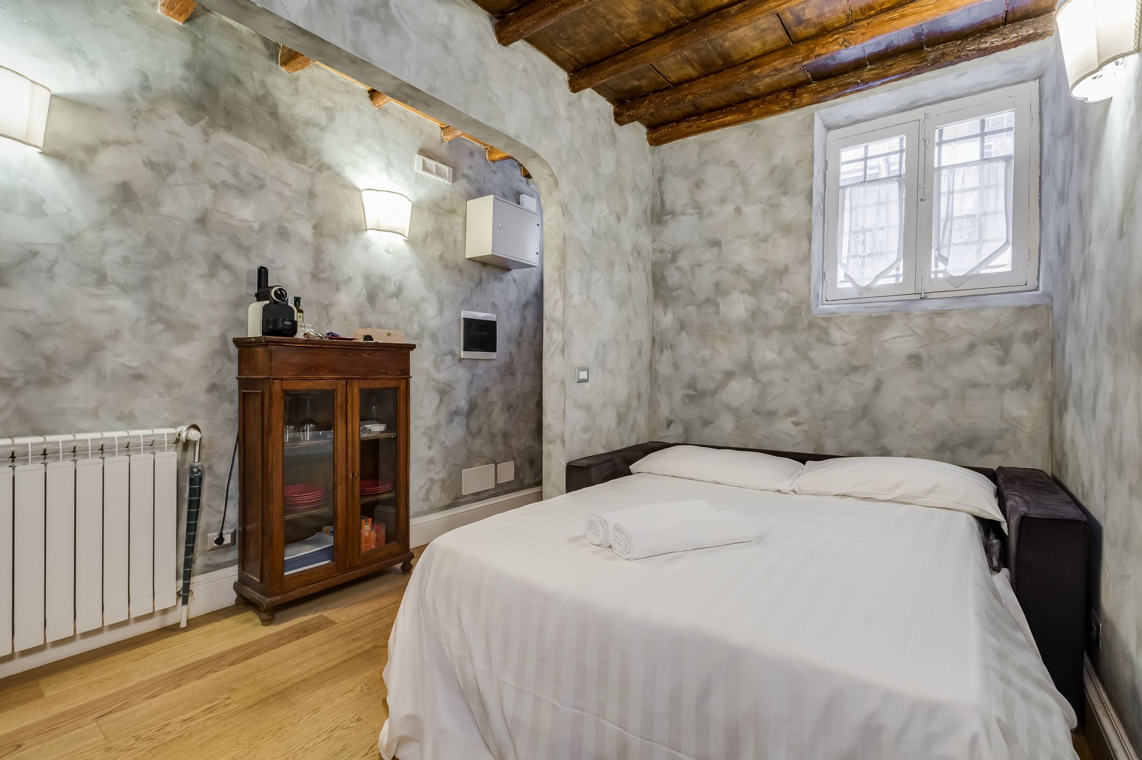 Une chambre à coucher avec un lit, une armoire en bois, un radiateur et une fenêtre.