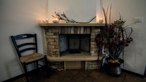 Ein Steinkamin mit einer Bank, einem Sessel, einer Kerze und einem Blumentopf.