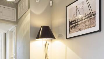 A hallway with a lamp, a framed photograph, and a white door.