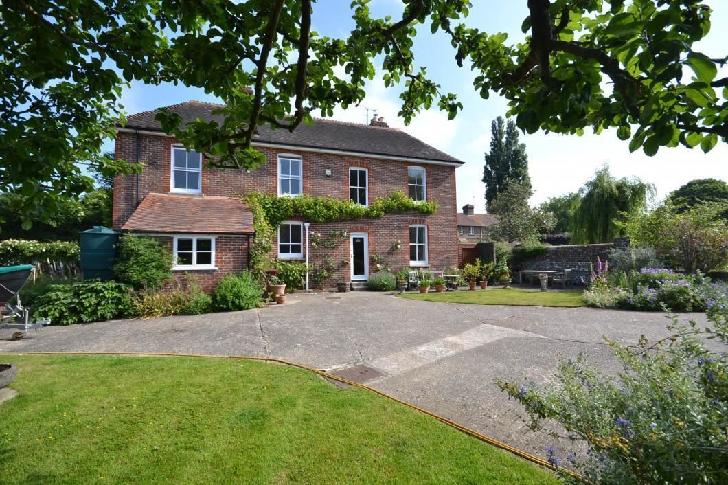 A two-story brick house with a paved driveway and a well-maintained garden.