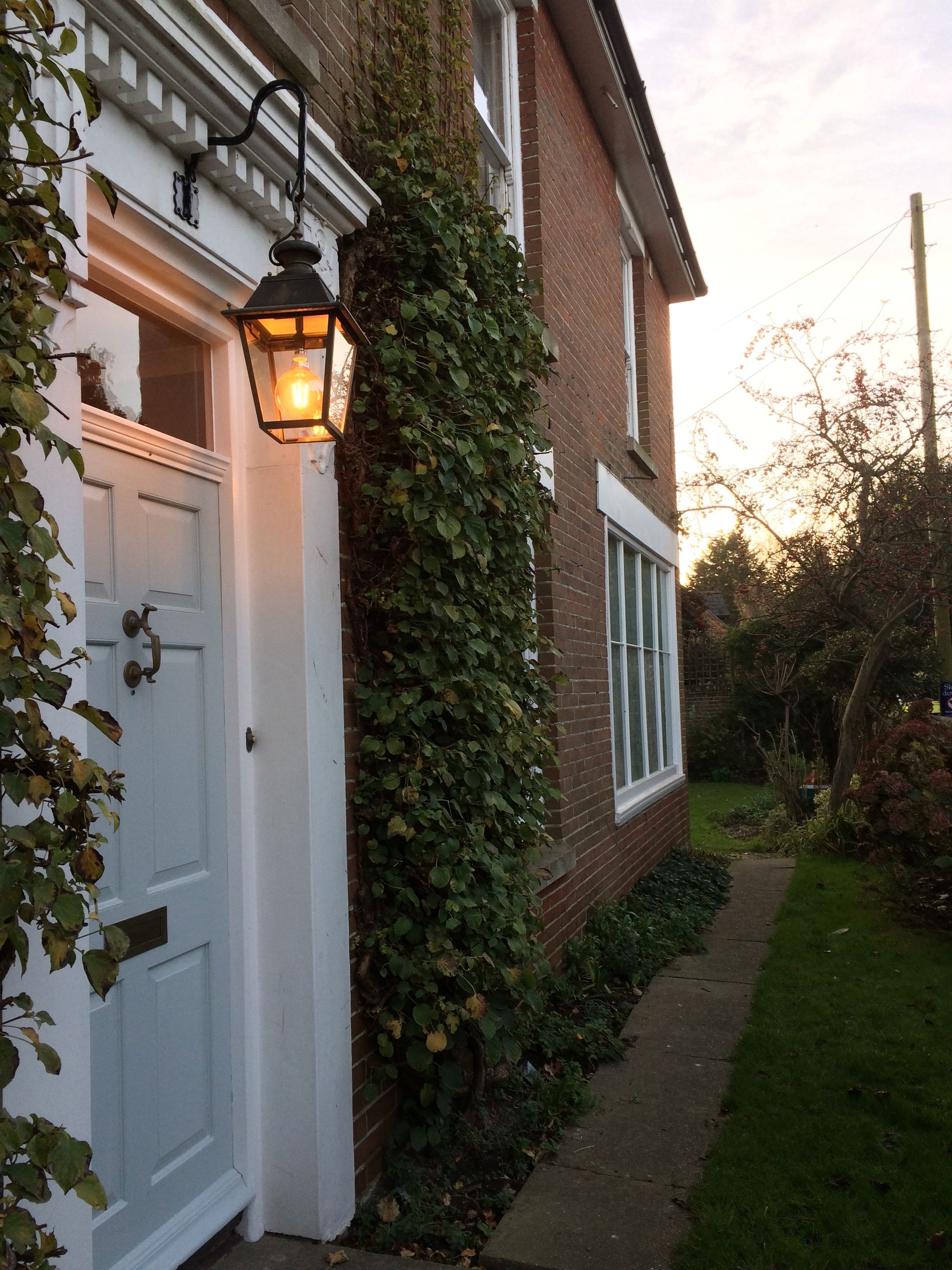 A white garage door, a brick house with ivy, and a pathway leading to a garden.