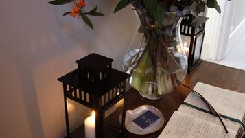 Una vela en un florero de vidrio, un farol negro y una libreta sobre una mesa de madera.