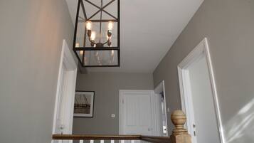 A staircase with a wooden handrail and a black metal chandelier with four bulbs.