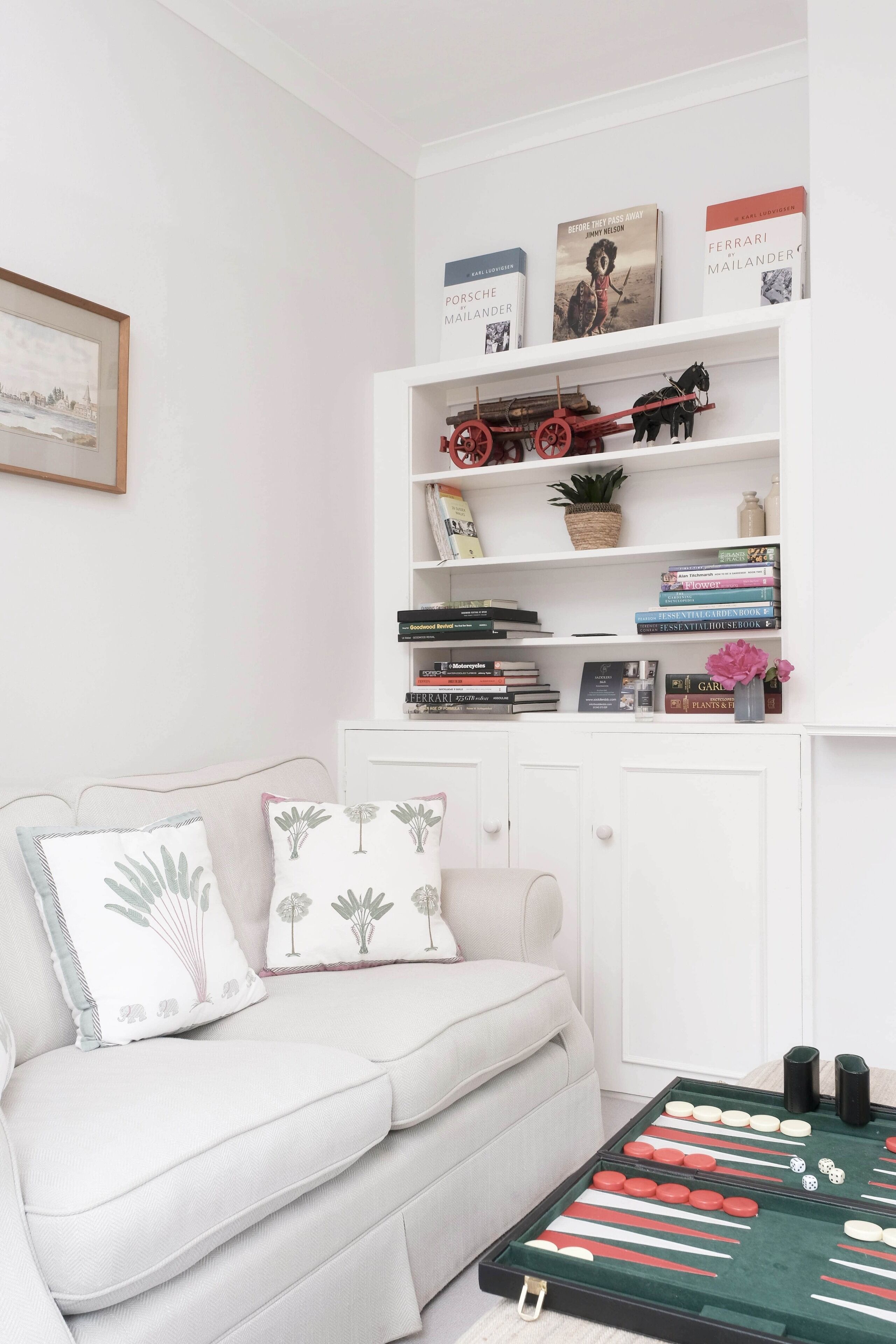 A living room with a white sofa, a small coffee table, and a bookshelf with books and decorative items.