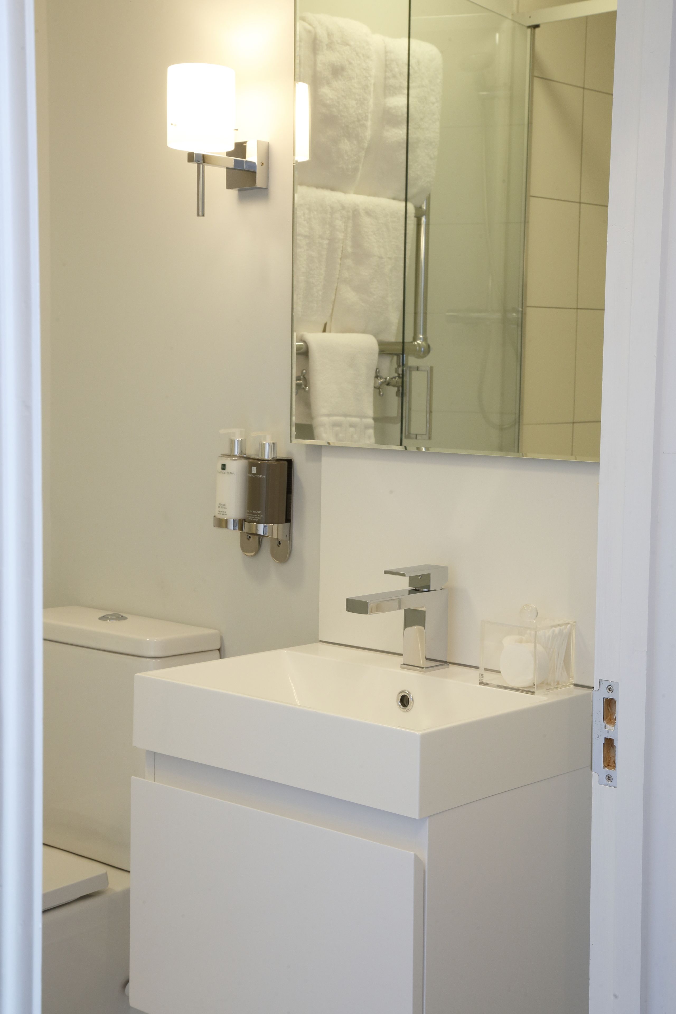 A modern bathroom with a white sink, a mirror, and a towel rack.