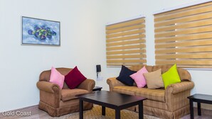 Two sofas with colorful cushions, a small table, and a painting on the wall. - Lake Bosumtwi Hotel & Apartments (Accra)