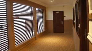 A hallway with wooden flooring, a door, and blinds on the windows. - Lake Bosumtwi Hotel & Apartments (Accra)