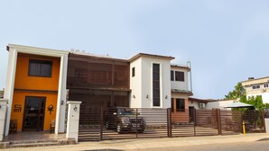 A modern two-story house with a garage, a car parked in front, and a gated entrance. - Lake Bosumtwi Hotel & Apartments (Accra)