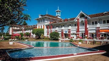 Una piscina al aire libre, sombrillas, sillones reclinables de piscina