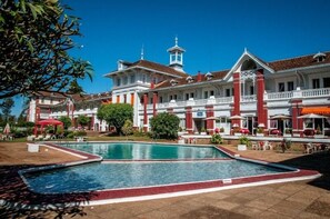 Un grand bâtiment doté d’une piscine, d’une façade rouge et blanche et de nombreux balcons.