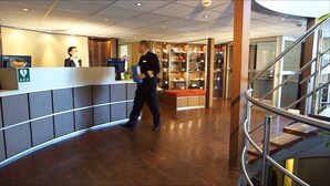 A hotel reception area with a reception desk, a staircase, and a display of various items. - Select MS Serenity - Neuss (Neuss)