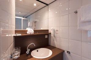 A modern bathroom with a white sink, wooden vanity, and a mirror. - Select MS Serenity - Neuss (Neuss)