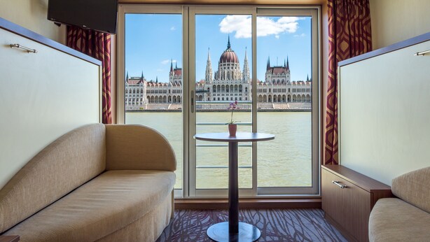 A room with a sofa, a small table, and a TV mounted on the wall. - Select MS Serenity - Neuss (Neuss)