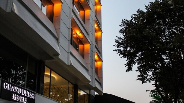 Exterior del Hotel Grand Bursa, con ventanas iluminadas y una vista clara de la entrada.