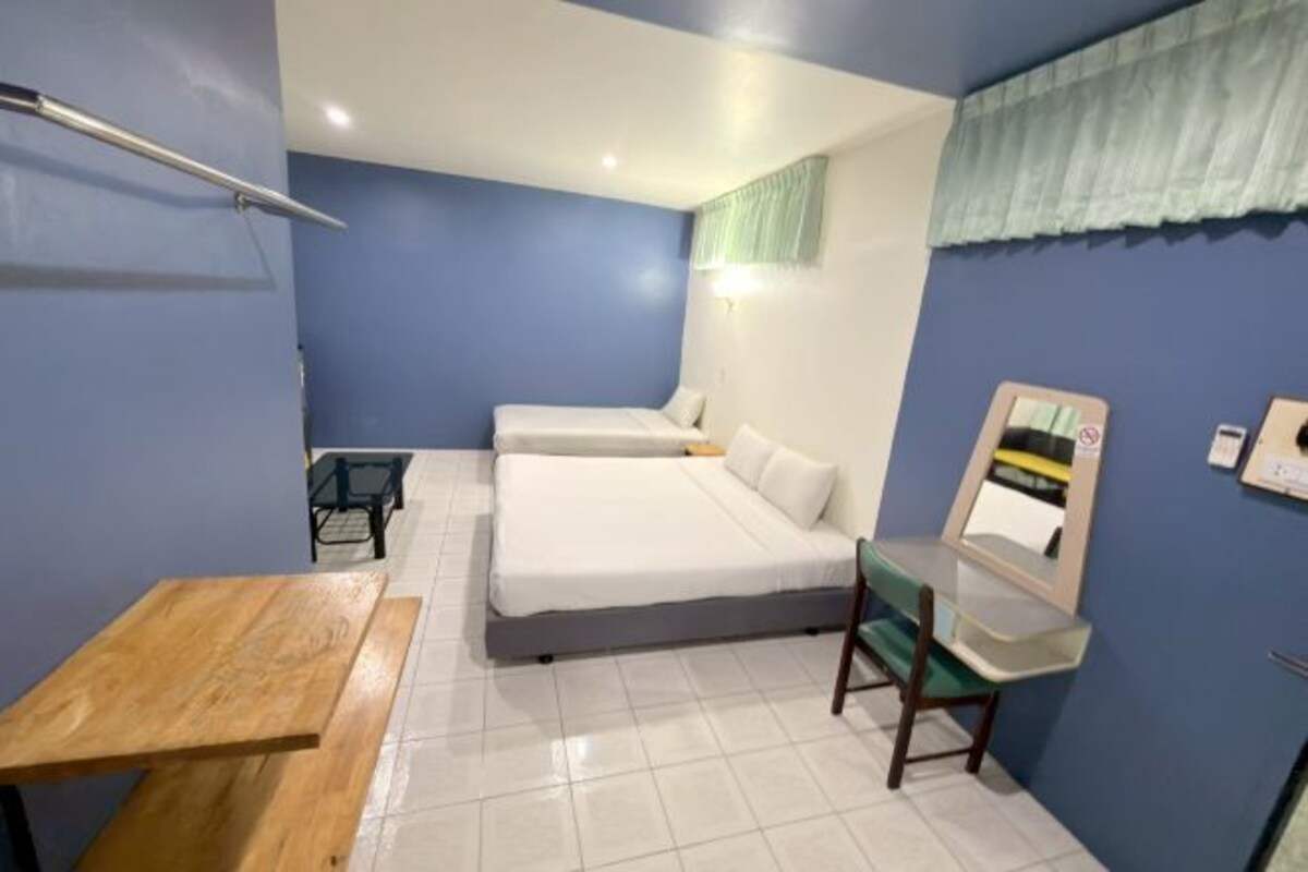 Habitación de hotel con cama, escritorio, silla, espejo y ventana con cortina.