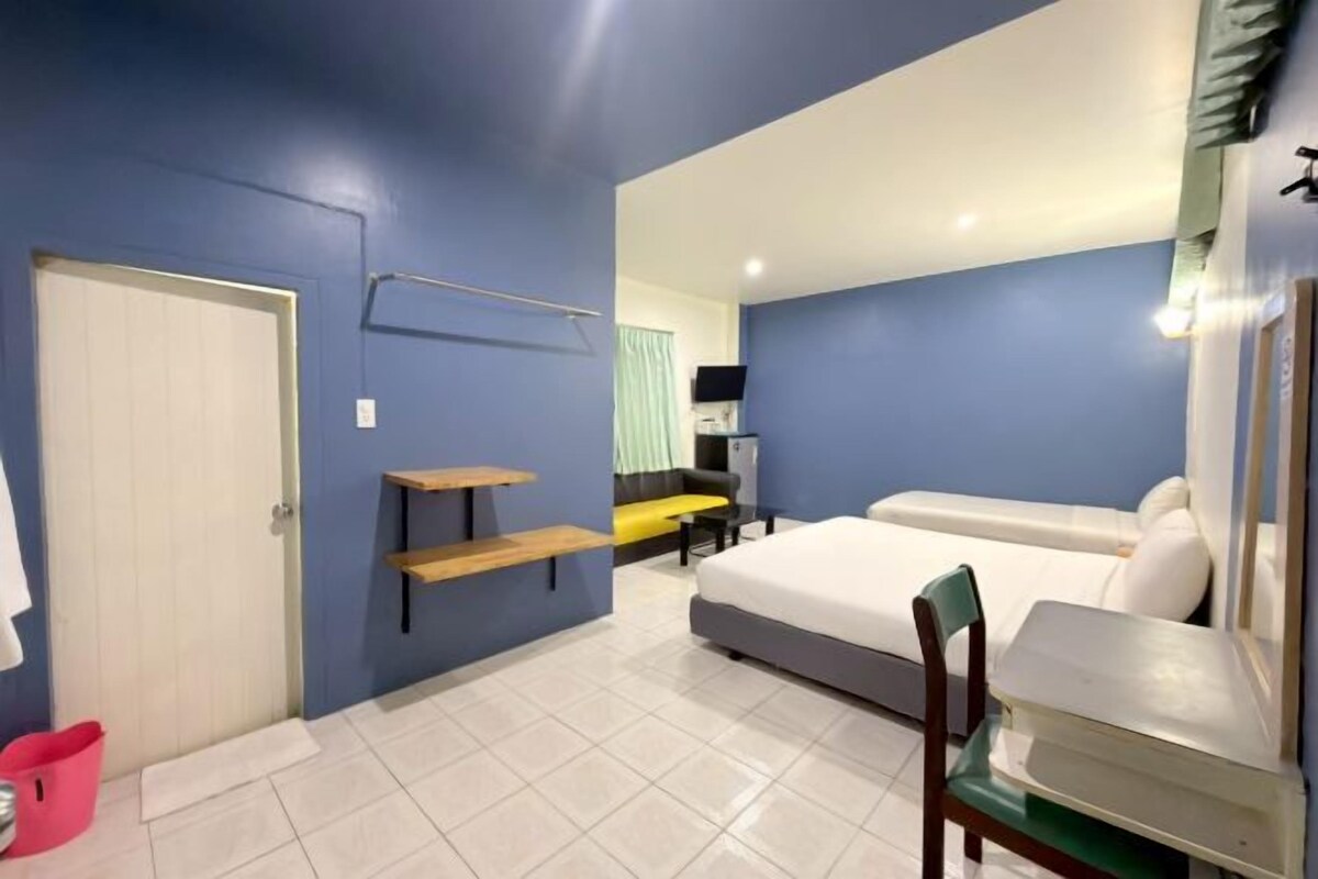 Un dormitorio con cama, una silla, escritorio, estante y puerta.