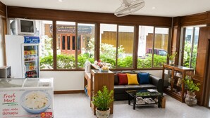 A hotel lobby with a sofa, a coffee table, a refrigerator, and a fan. - V.House Nakhon (Nakhon Si Thammarat)