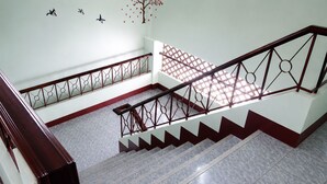 A multi-level staircase with a patterned glass floor, metal railings, and a wall with bird decals. - V.House Nakhon (Nakhon Si Thammarat)