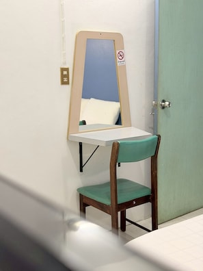 A small room with a wooden chair, a white table, a mirror, and a door. - V.House Nakhon (Nakhon Si Thammarat)