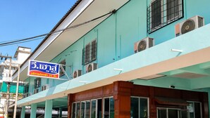 A building with a sign indicating a 5-star hotel, a covered entrance, and parked cars. - V.House Nakhon (Nakhon Si Thammarat)