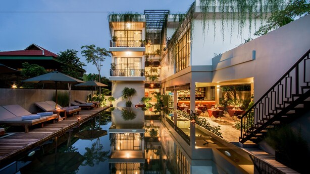 A modern hotel with a reflective pool, outdoor seating, and a staircase. - VIHARA The City of Temples (Siem Reap)