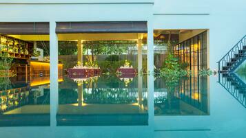 Een buitenzwembad, parasols bij het zwembad en ligstoelen