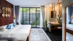 Una habitación de hotel moderna con una cama grande, un baño con lavamanos y espejo, y vista a zonas verdes.