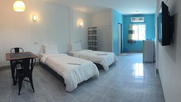 A hotel room with two beds, a desk, and a TV. - Blue Hip Apartment Nakhon Sri (Nakhon Si Thammarat)