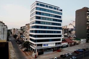 A modern hotel with a prominent 'BLU SKY' sign, multiple floors, and a parking lot with various vehicles. - Blu Sky Hotel (Maputo)