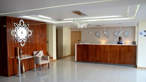 A modern reception area with a wooden reception desk, a glass table, and a leather chair.