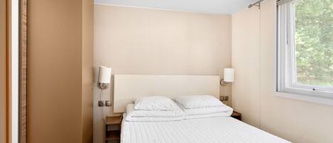 Une chambre à coucher avec un lit, des lampes de chevet, une fenêtre et une porte.