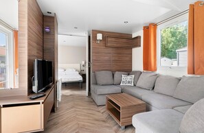 A modern living room with a grey sofa, wooden TV stand, and a flat-screen TV. - First Camp Lilleby (Torslanda)