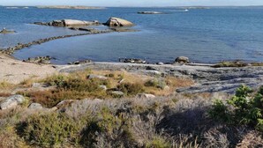 Een kustlandschap met rotsachtig terrein en rustig water.