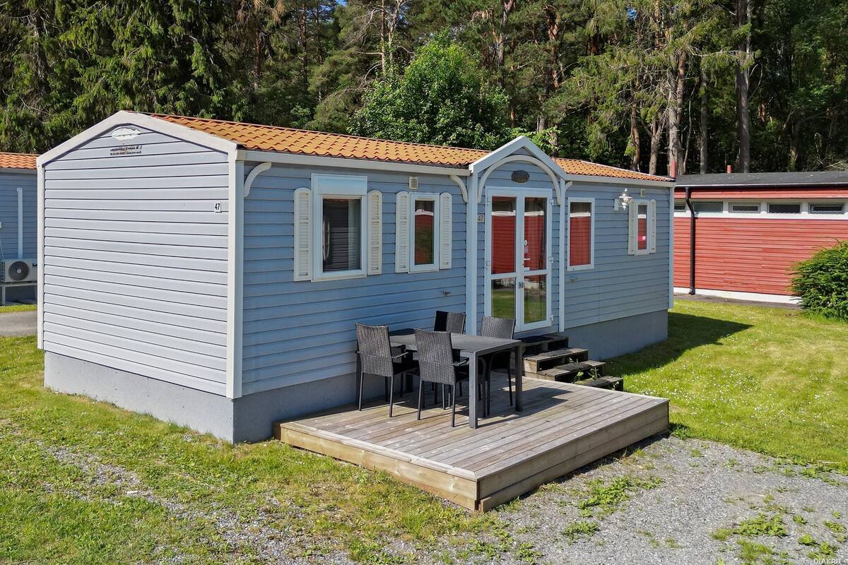 Een klein, gelijkvloers huisje met een veranda en een tafel met stoelen.