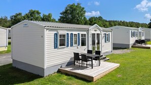 Een rij vakantiewoningen met een terras, elk voorzien van een deur en ramen met luiken.