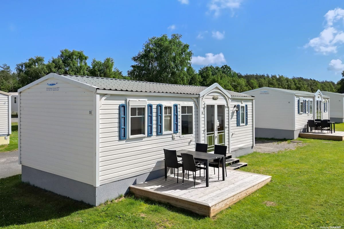 Een rij vakantiewoningen met een terras, elk voorzien van een deur en ramen met luiken.