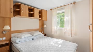 Een slaapkamer met een bed, houten kasten, een nachtkastje en een raam met gordijnen.