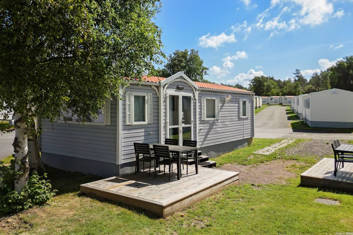 Een stacaravan met een veranda en een zitgedeelte buiten.