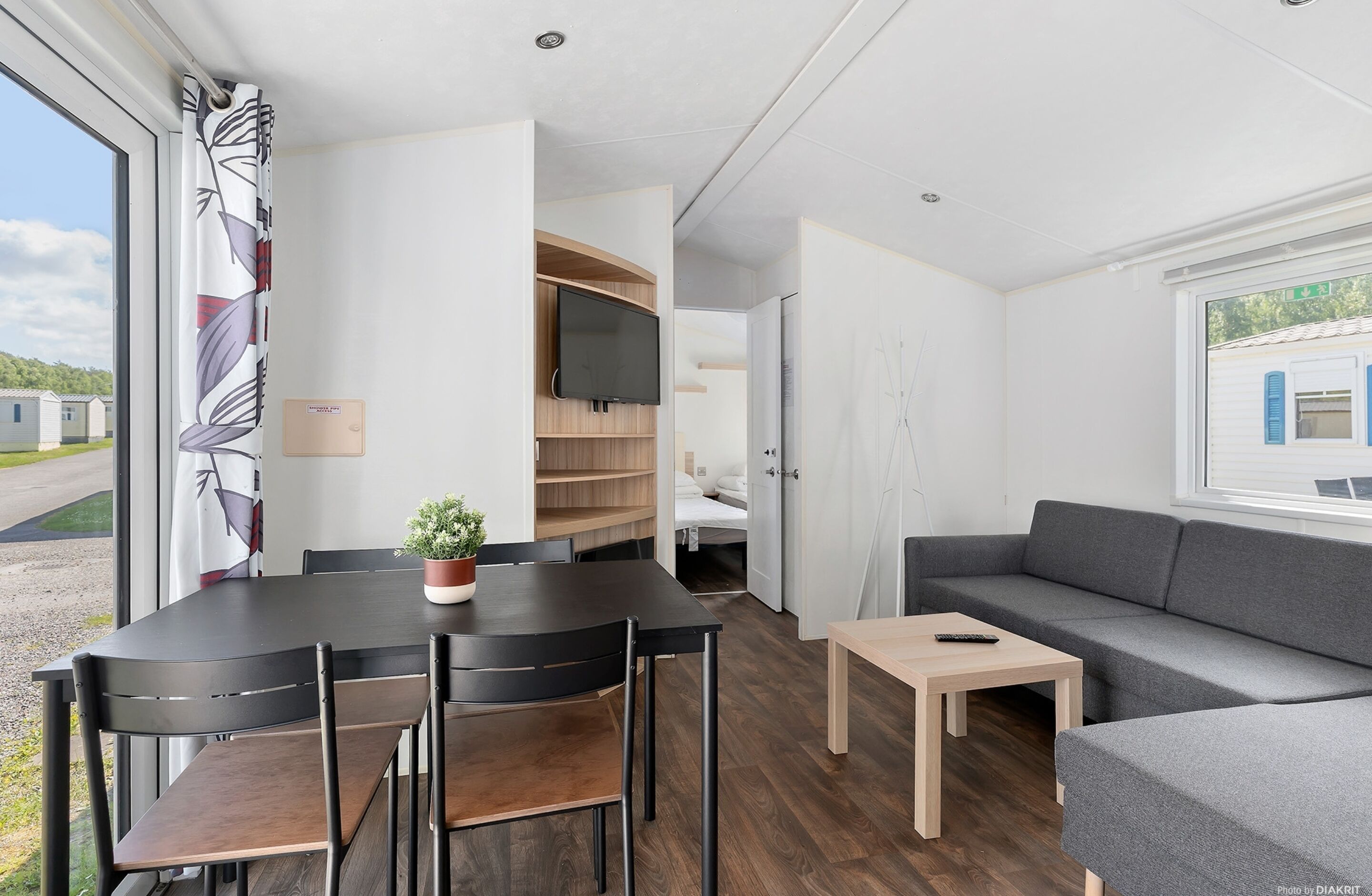 Una habitación moderna y luminosa con una mesa de comedor, sillas, un sofá y un televisor montado en la pared.