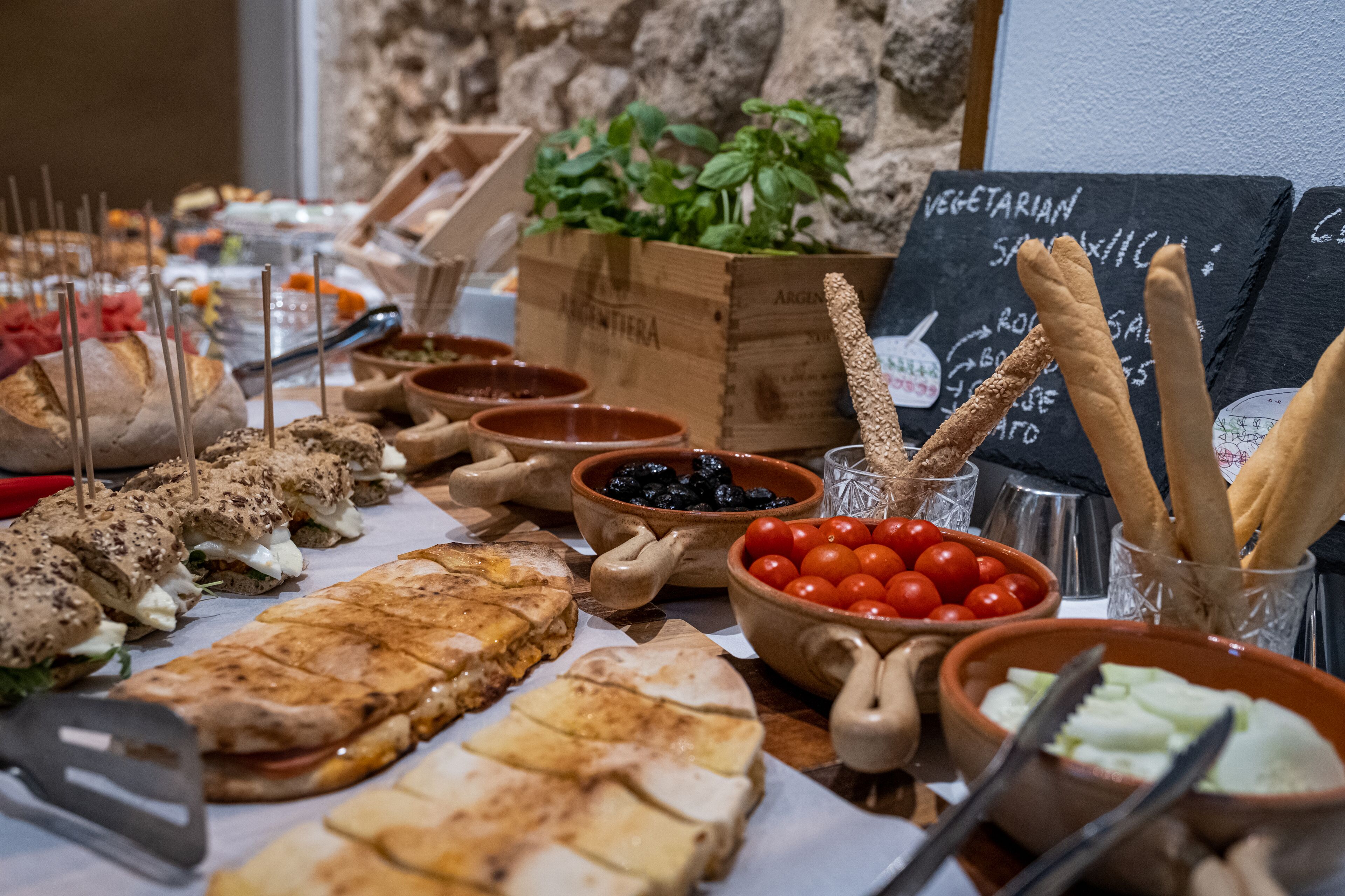 Un buffet proposant une variété de plats, notamment des sandwichs, des salades et des bâtonnets de pain.