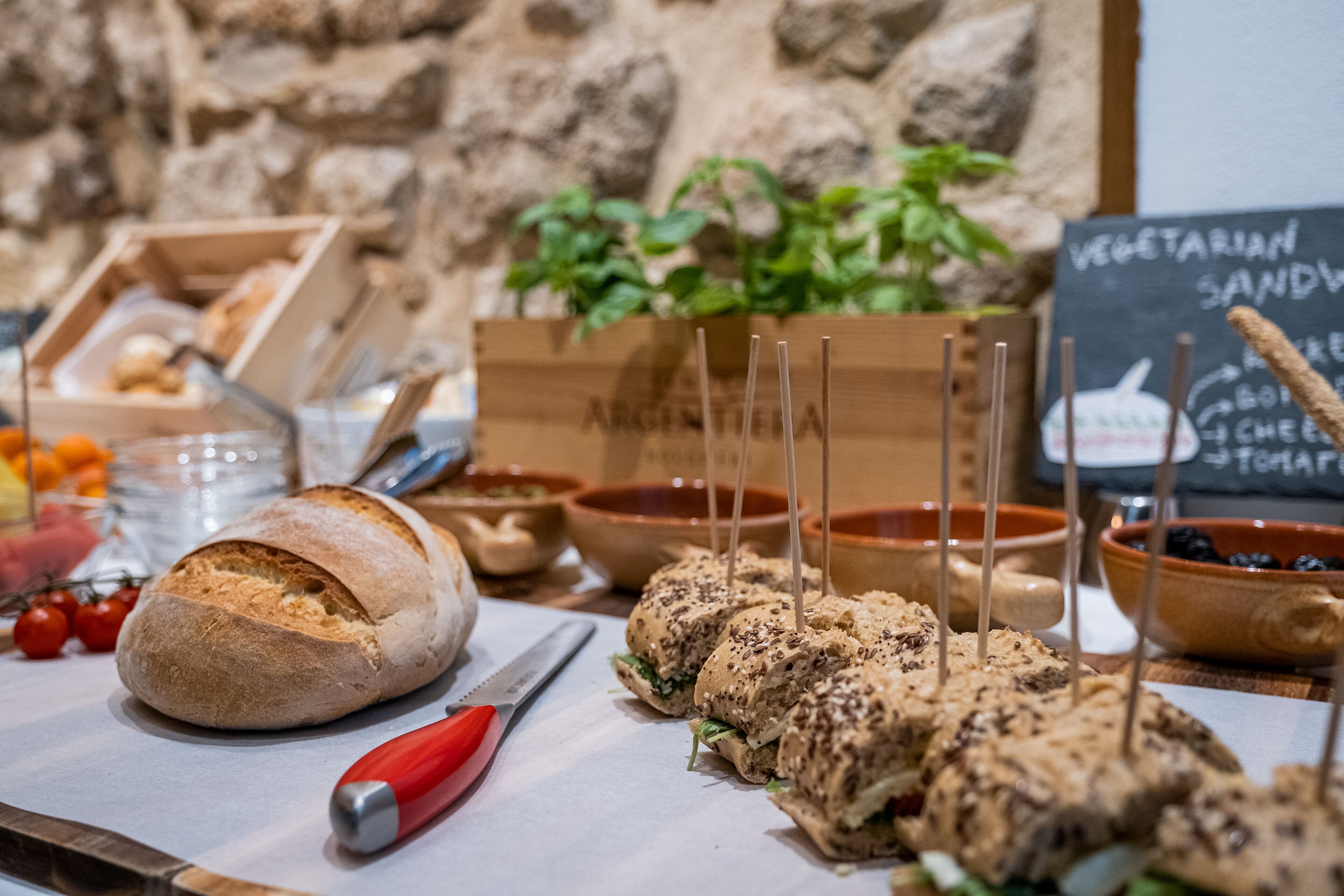 Una mesa con sándwiches, pan y diferentes fuentes de comida.