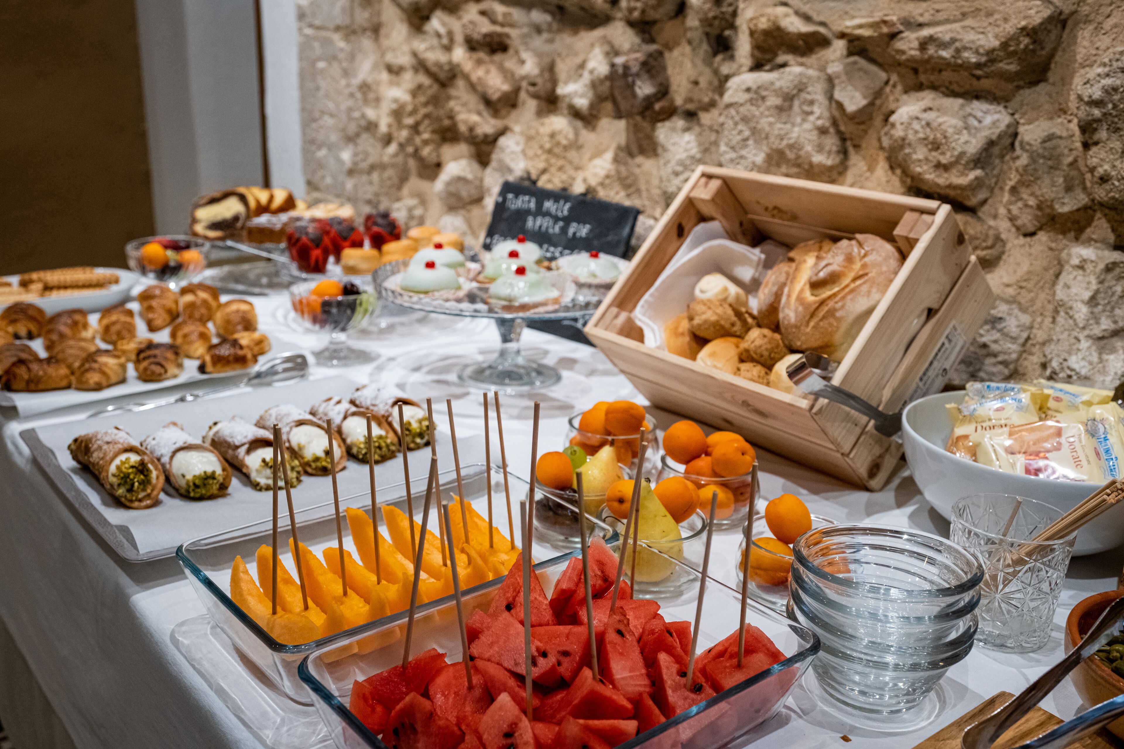 A buffet with various food items including pastries, fruits, and desserts.