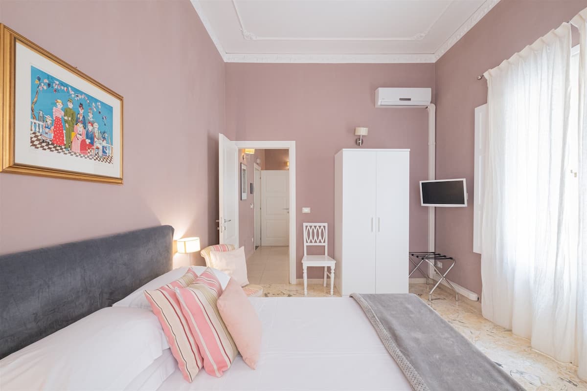 A bedroom with a bed, a chair, a television, and a wardrobe.