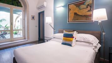 A hotel room with a bed, a painting, two lamps, and a door leading to a balcony.