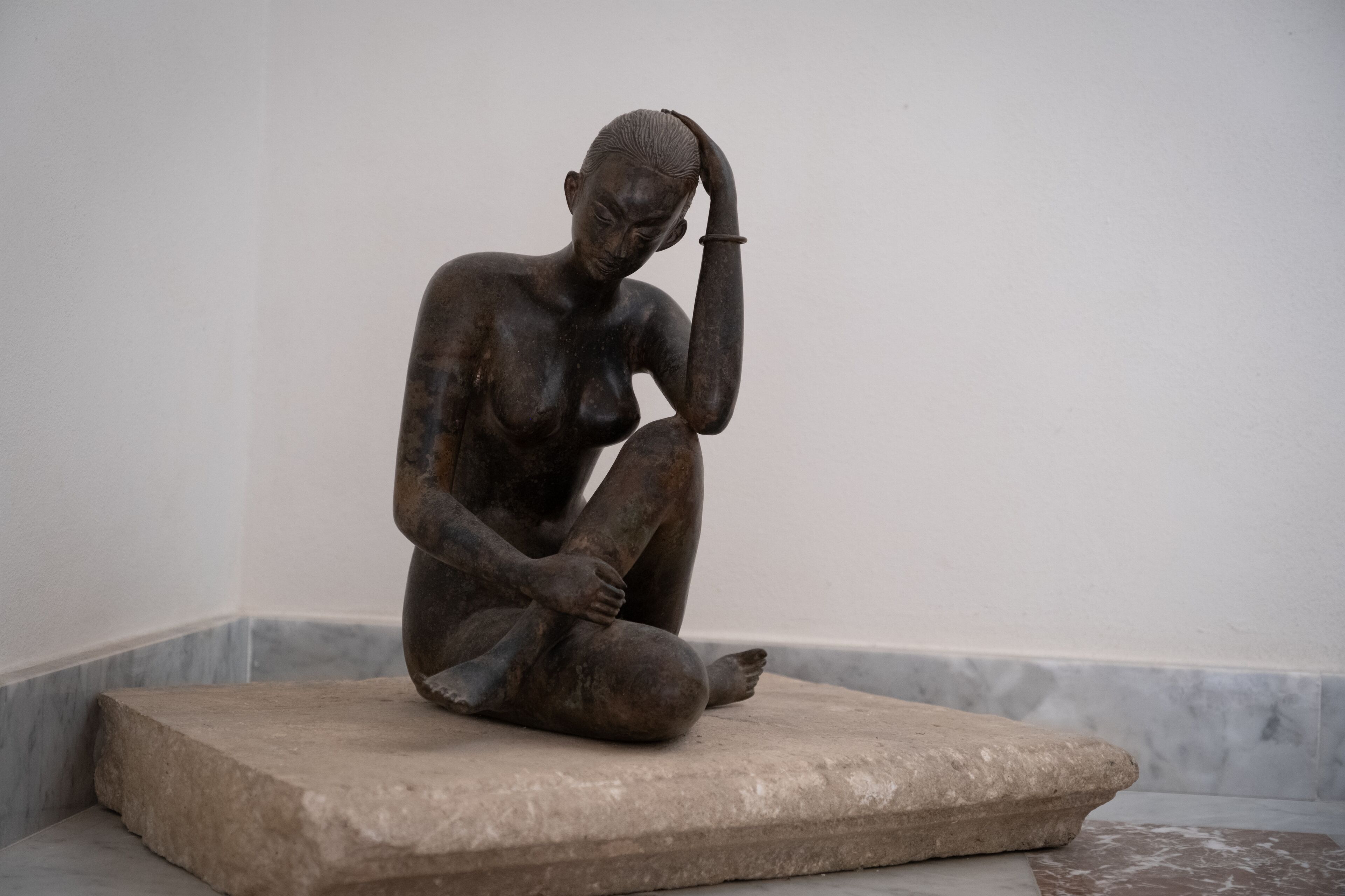 A sculpture of a seated figure on a stone platform.