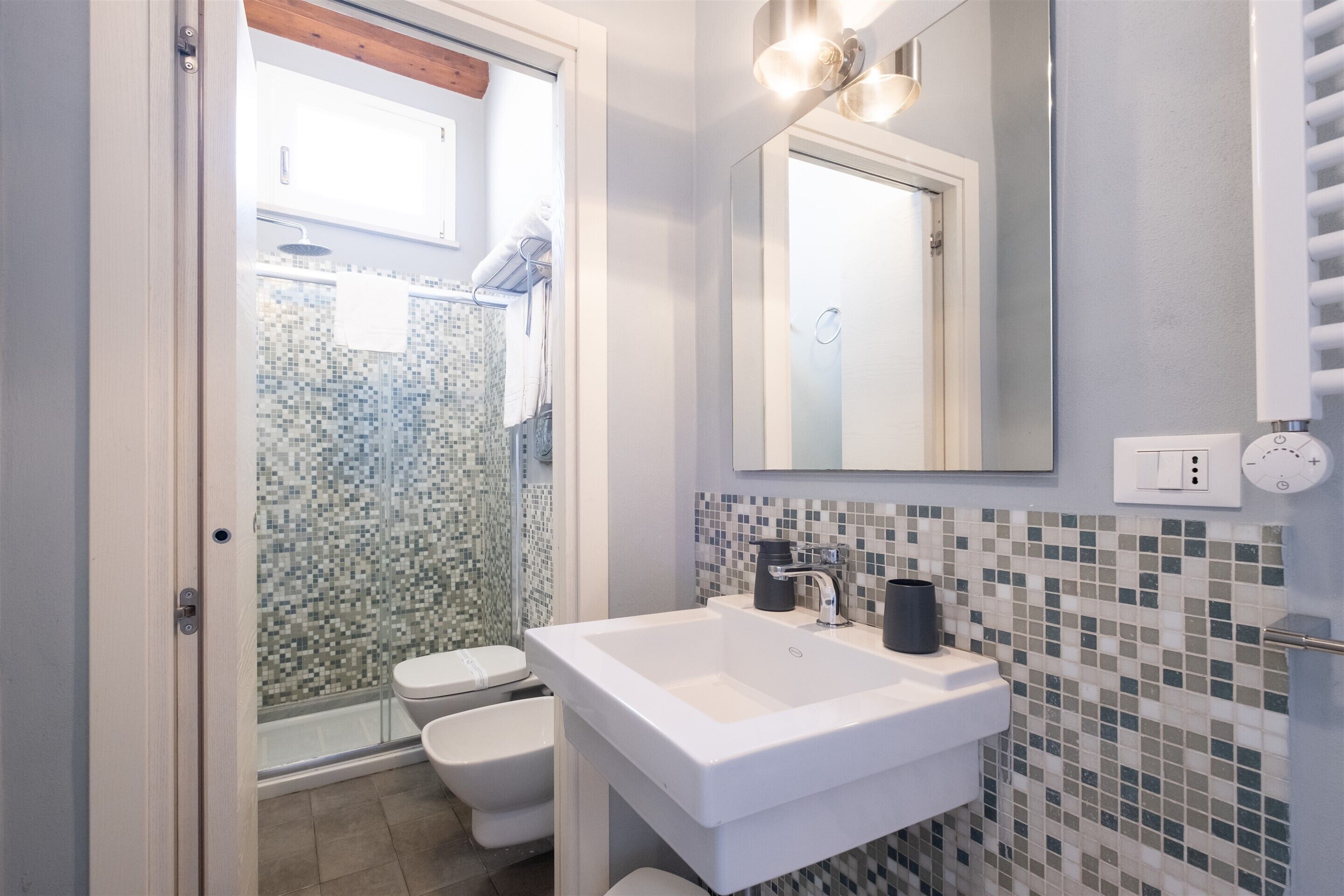 Une salle de bain avec un lavabo blanc, un miroir et un espace douche.