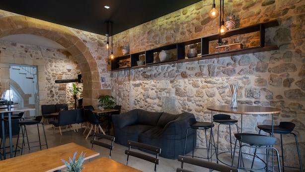 A cozy restaurant with stone walls, wooden tables, and a dark-colored sofa. - Palazzo Gilistro (Syracuse)